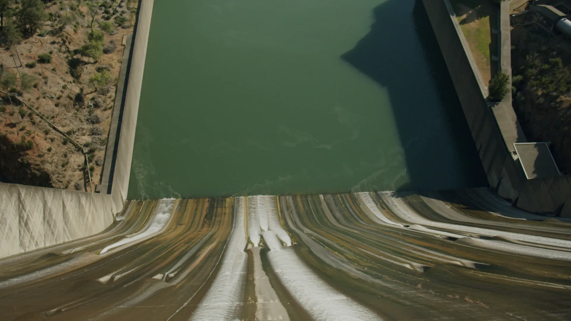 Top down image of a canal next to a dam.